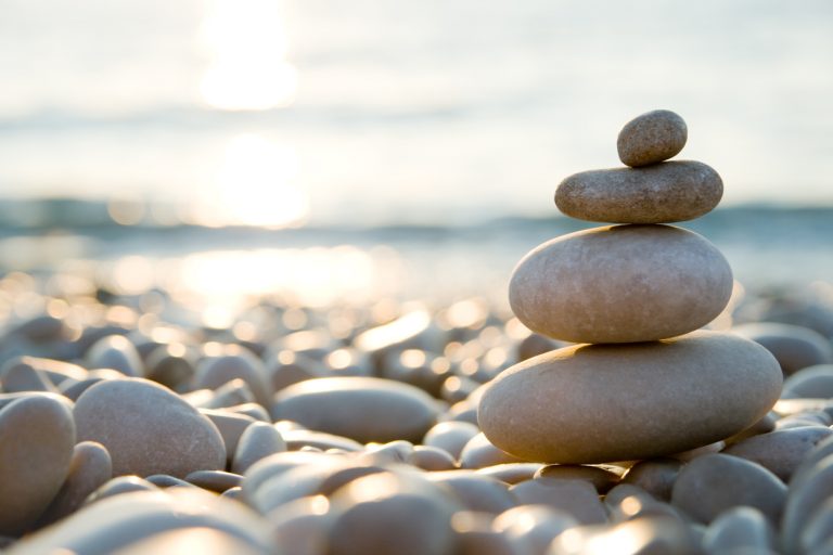 Balanced stones on a pebble beach during sunset